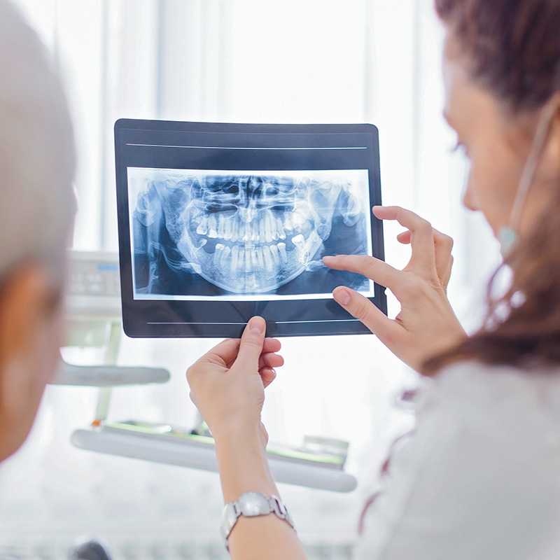 Female dentist examining patient x-ray and talking to a patient