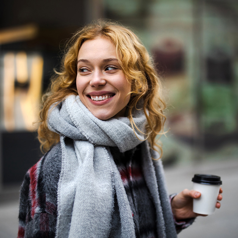 Young woman with coffee cup smiling outdoors