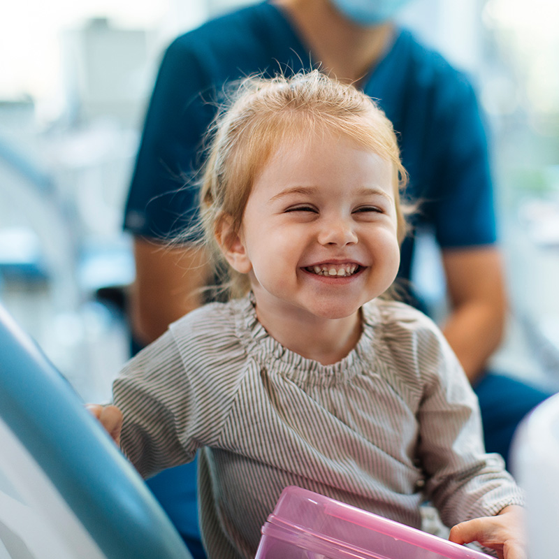 Smiling young girl sitting in a dental chair in her dentists office